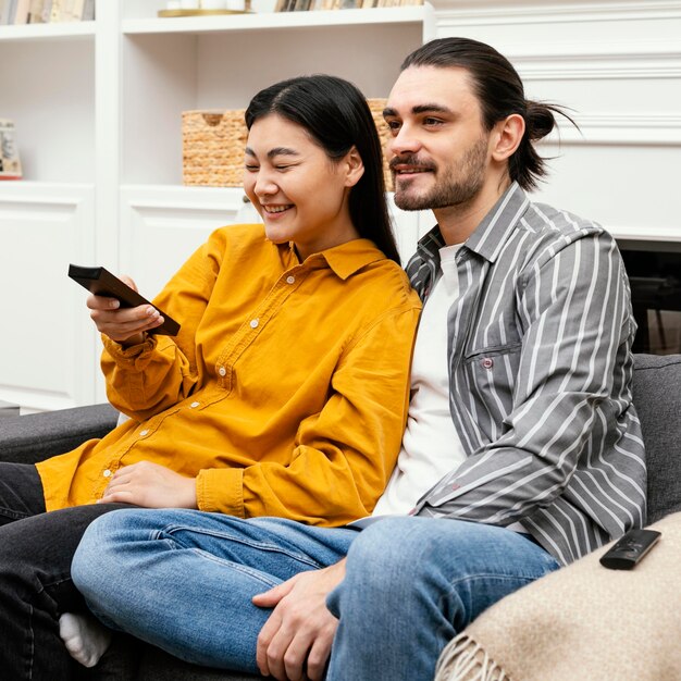 Couple sitting on the couch watching tv side view