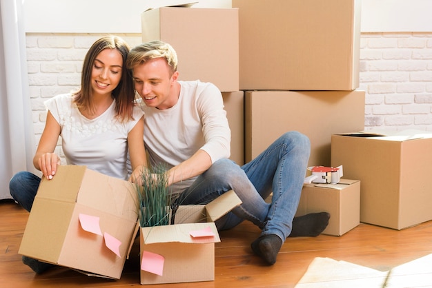 Couple sitting on the floor inspect a box