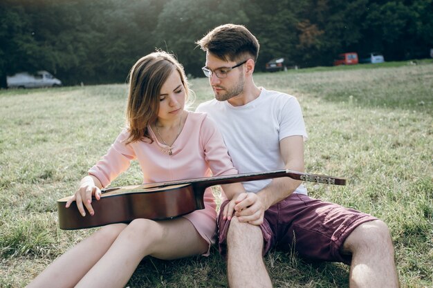 Couple sitting on the grass with a guitar