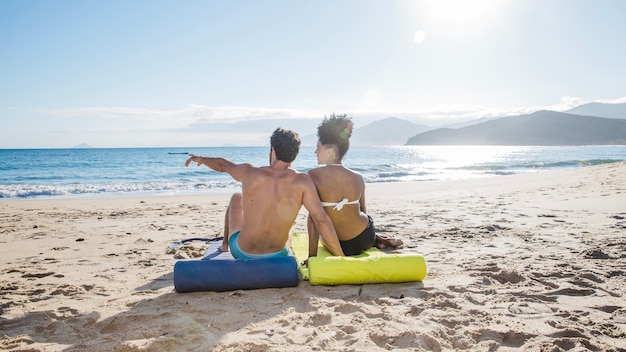 Couple sitting and pointing at the beach