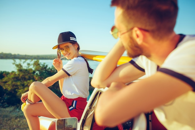 Couple sitting and resting on the beach on a summer day near river. Caucasian man and woman