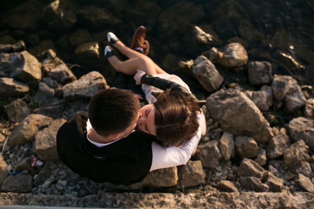 Free Photo couple sitting on the rocks by the sea