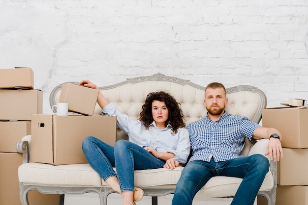 Couple sitting on sofa near carton boxes