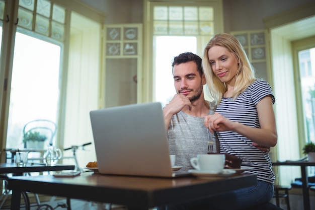 Couple sitting at table and using laptop