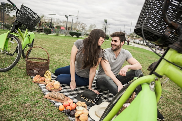 Free Photo couple sitting together in the park enjoying at picnic