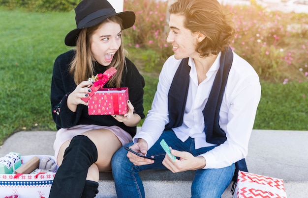 Free photo couple sitting with gift box on bench