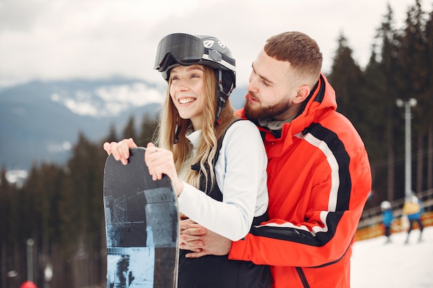 Free Photo couple in snowboard suits. sports people on a mountain with a snowboard in the hands on the horizon. concept on sports