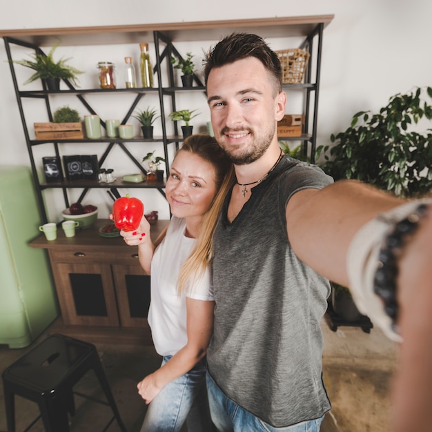 Couple standing in kitchen taking selfie