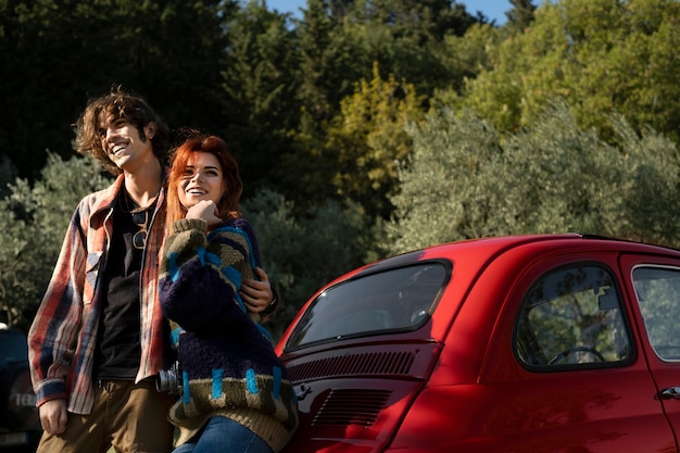 Couple standing near car medium shot