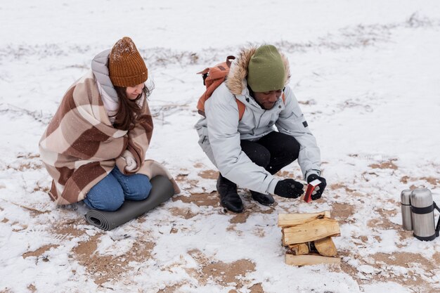 Couple starting a fire on the beach during a winter road trip to warm up