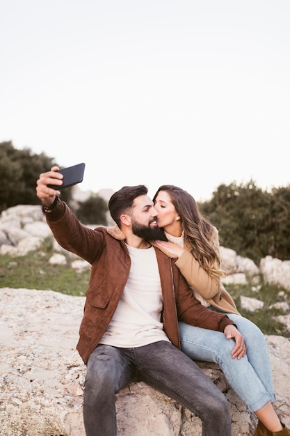 Couple staying on a rock and taking a selfie