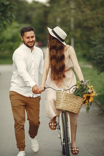 Couple in a summer park. People with vintage bicycle. Girl in a hat.