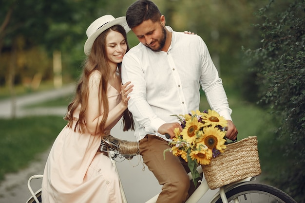 Couple in a summer park. People with vintage bicycle. Girl in a hat.