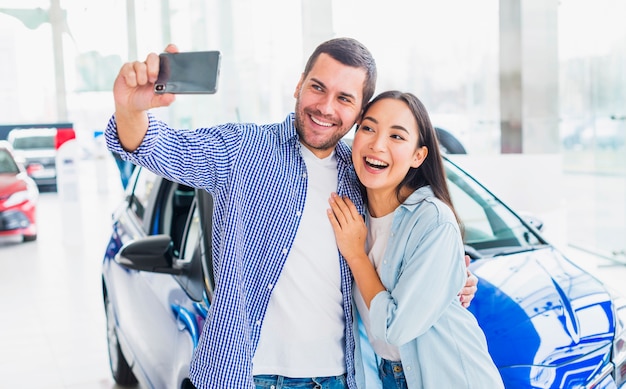 Couple taking selfie in car dealership