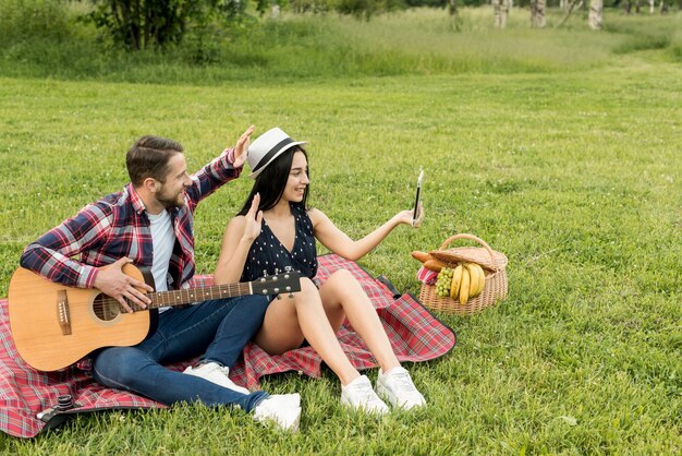 Couple taking a selfie on a picnic blanket