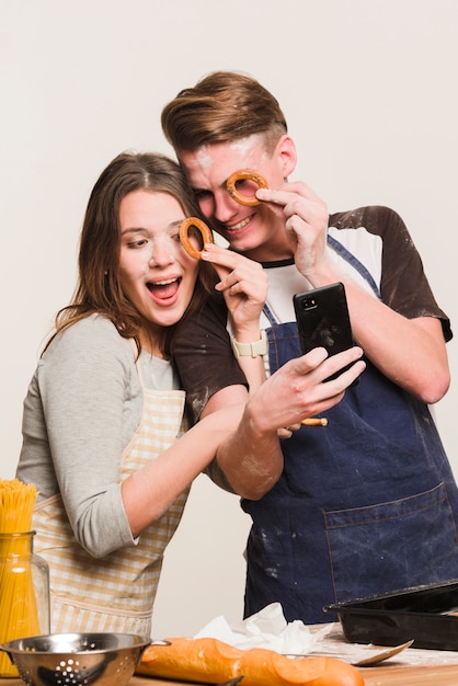 Couple taking selfie with round crackers near eyes 