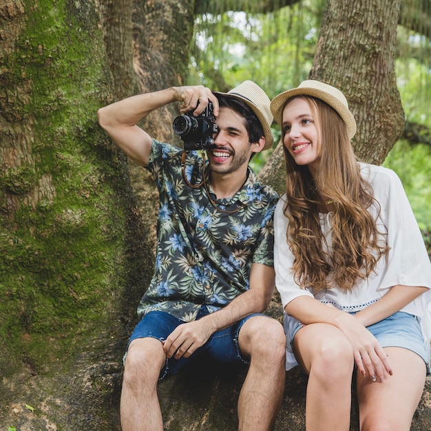 Couple on tree root with camera