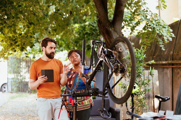 Free photo couple using tablet for bicycle maintenance