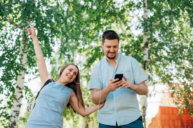 Couple walking in birch forest with headphones