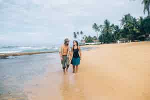 Free photo couple walking on sandy shore