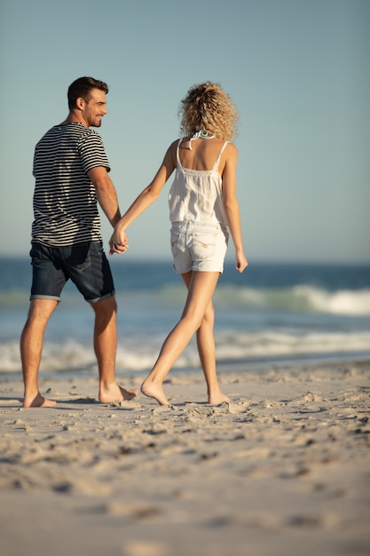 Couple walking together hand in hand on the beach