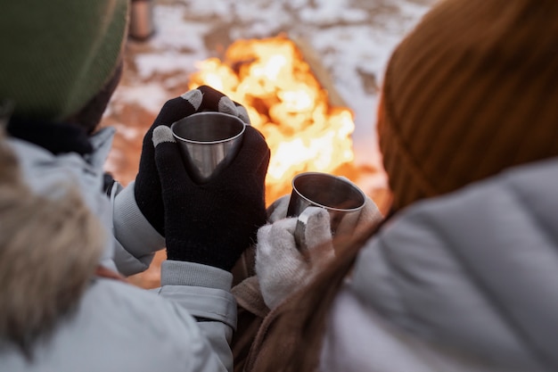 Free photo couple warming up next to fire on the beach while on a winter road trip