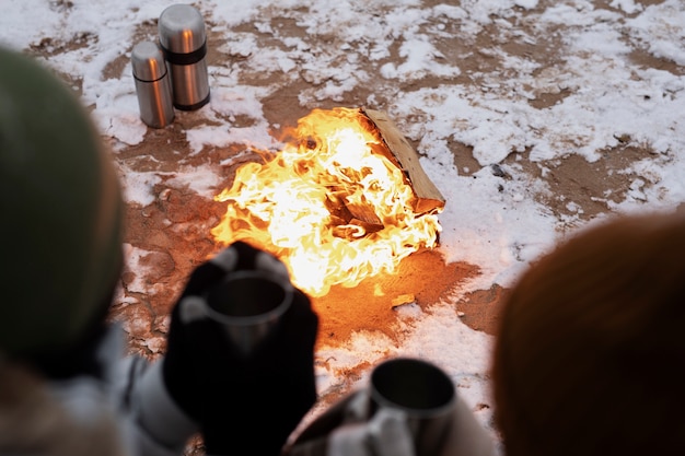 Free Photo couple warming up next to fire on the beach while on a winter road trip