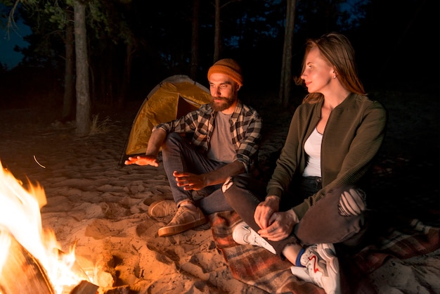 Free Photo couple warming up at night by a campfire