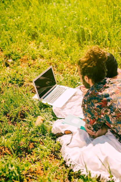 Free photo couple watching into laptop in field