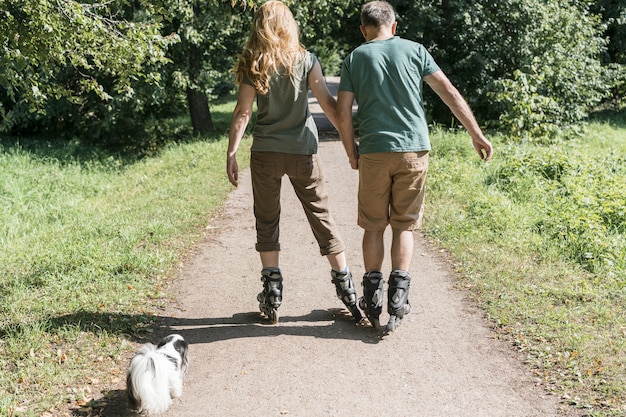 Free photo couple wearing roller skates walking in the park