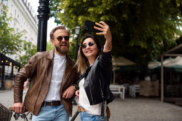 Couple wearing synthetic leather jackets taking selfie together outdoors