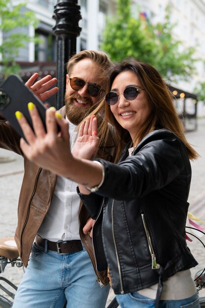 Couple wearing synthetic leather jackets taking selfie together outdoors