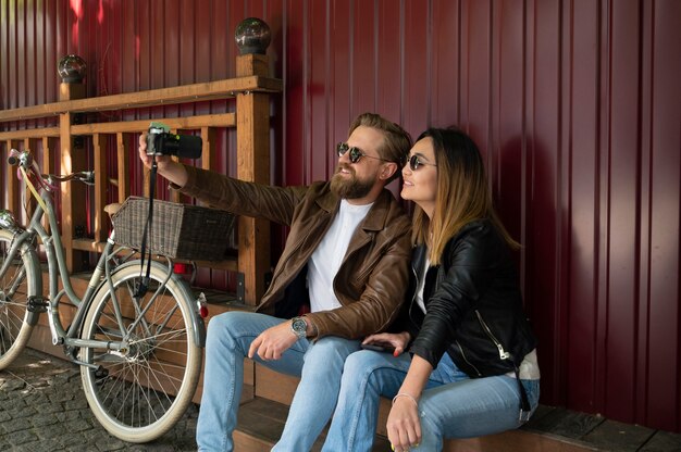 Couple wearing synthetic leather jackets taking selfie together outdoors