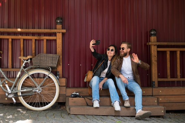 Free photo couple wearing synthetic leather jackets taking selfie together outdoors