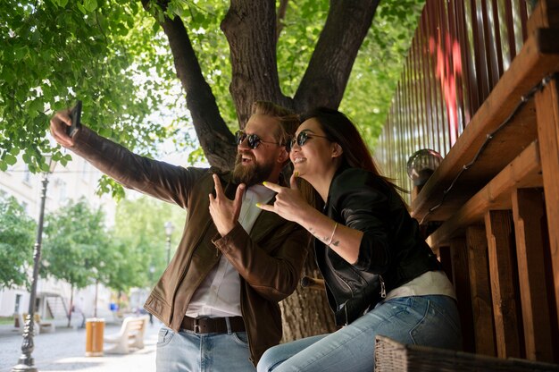 Couple wearing synthetic leather jackets taking selfie together outdoors