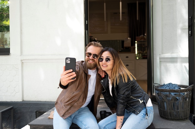 Free photo couple wearing synthetic leather jackets taking selfie together outdoors