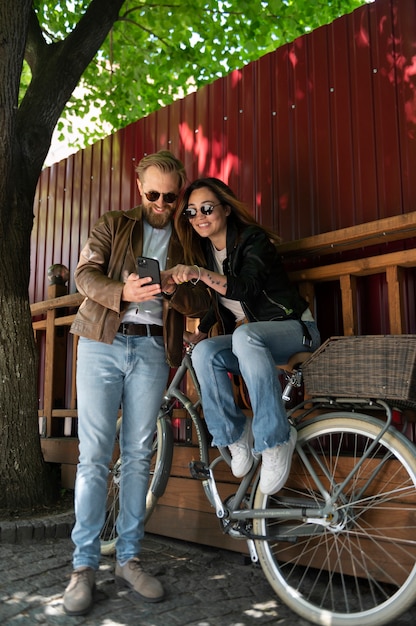 Couple wearing synthetic leather jackets and using smartphone outdoors