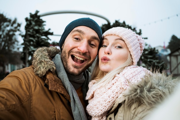 Free photo couple in winter blowing a kiss