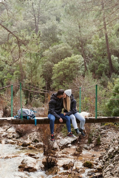 Couple with backpack sitting on bridge