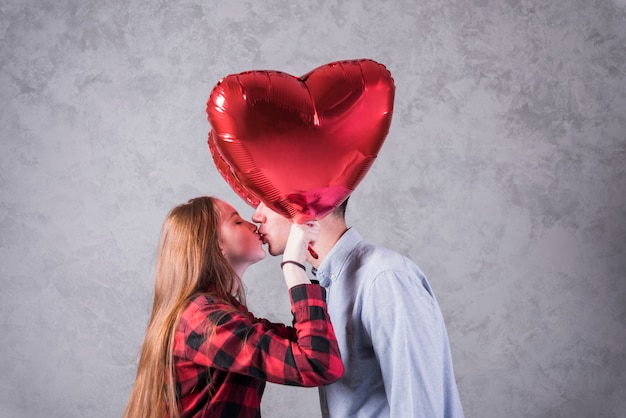 Free Photo couple with balloons in heart shape kissing 