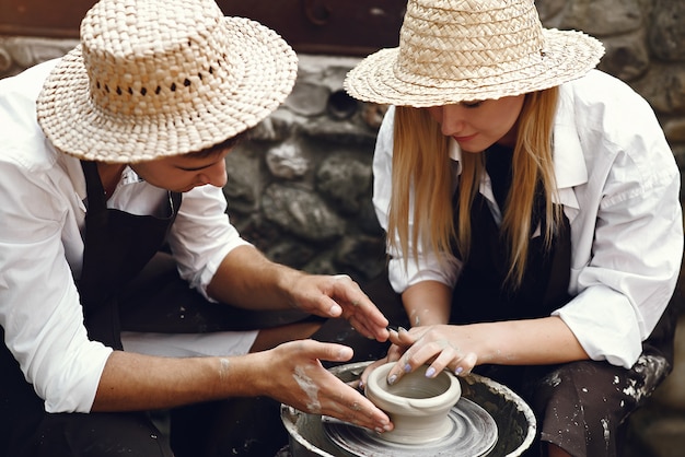 Couple with brown aprons making a vase