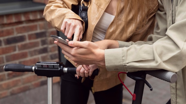 Couple with electric scooters  and smartphone outdoors