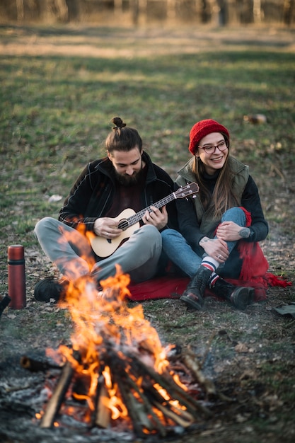 Free Photo couple with guitar near campfire