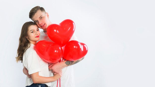 Couple with heart balloons hugging