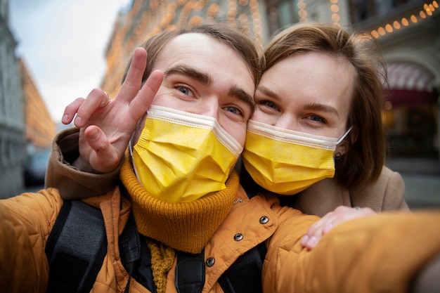 Couple with masks taking selfie in city