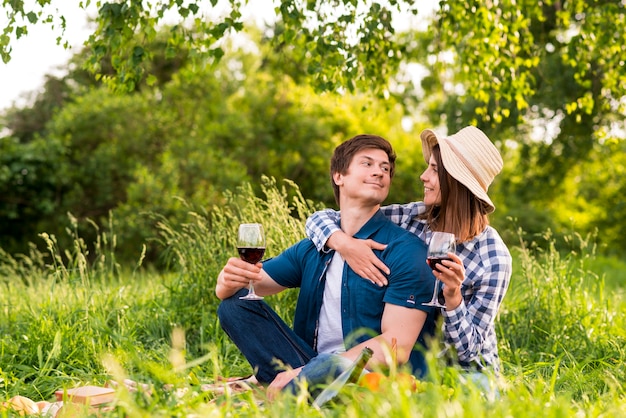 Couple with wine glasses hugging in nature