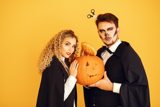 Free Photo couple on a yellow background. woman wearing black costume. lady with halloween makeup.