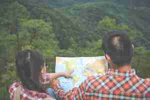 Free photo couples see a map in a tropical forest with backpacks in the forest. adventure, hiking, climbing.