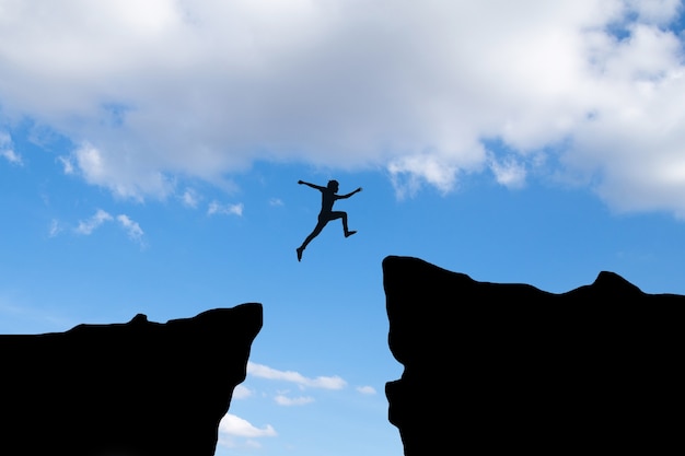 Free photo courage man jump through the gap between hill ,business concept idea