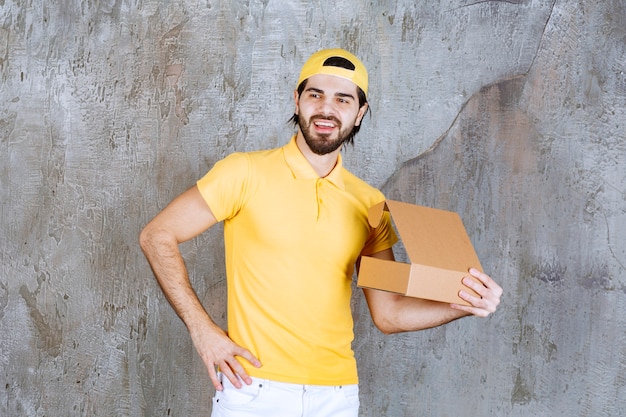 Free photo courier in yellow uniform holding an open cardboard box